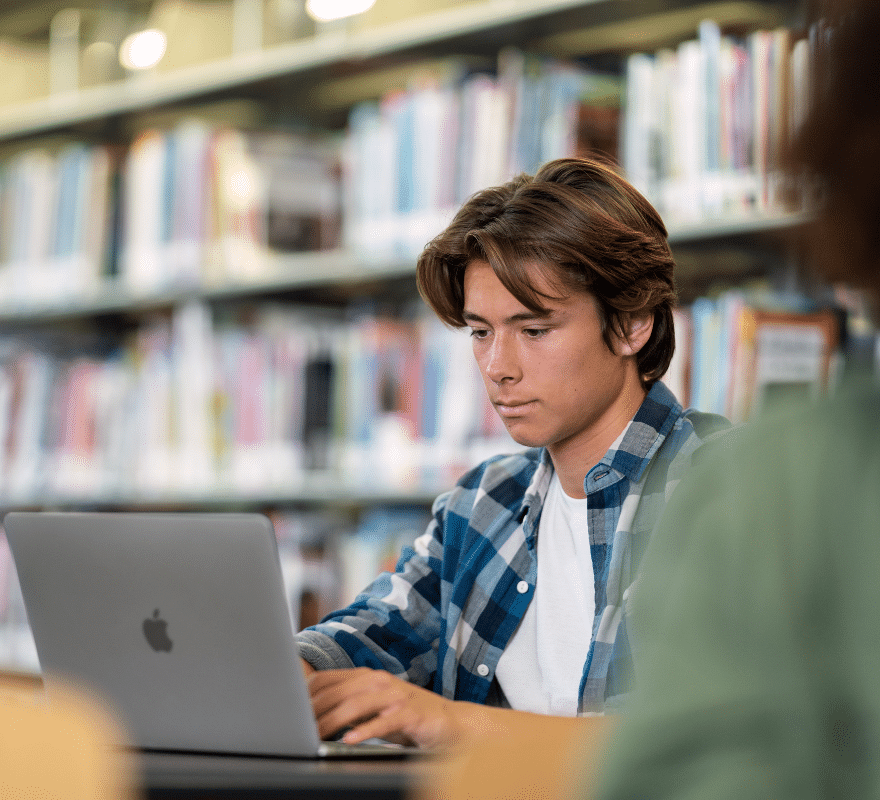 A student working on his MacBook in the library